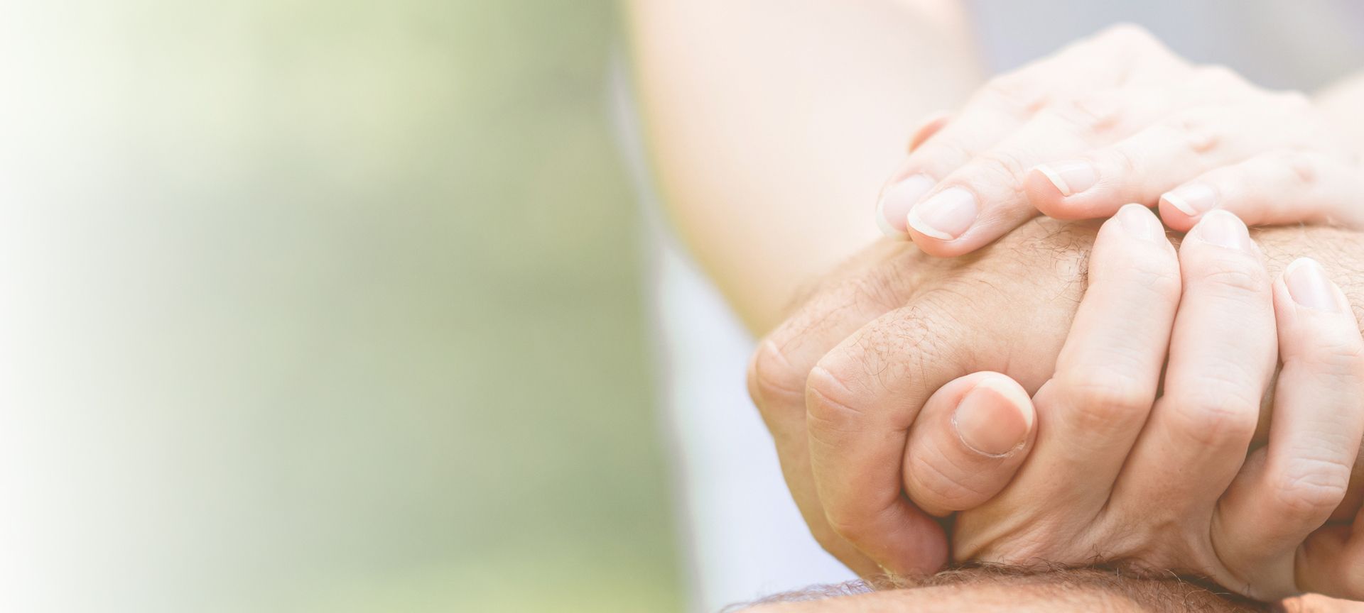 Die Hände einer jungen Person halten die Hand einer älteren Person fest umschlossen